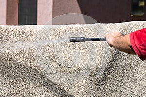 Close up of washing carpets with high pressure washer. Cleaning the carpet with a gun for washing high pressure water. House