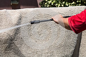 Close up of washing carpets with high pressure washer. Cleaning the carpet with a gun for washing high pressure water. House