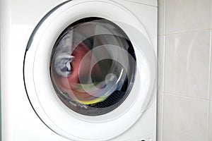 Close-up Of Washing Machine Door With Multicolored Clothes Rotating Inside with copy space washing and dryer machine