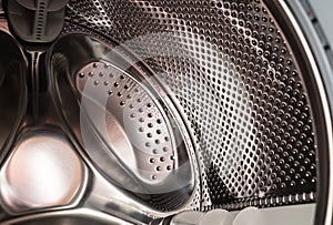 Close-up of a washing machine drum with the door open to dry and ventilate inside the washer.