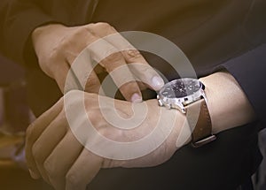 Close-up of watch on wrist of man. Men in black shirt looking at his luxury watches brown leather strap that are worn in the hands