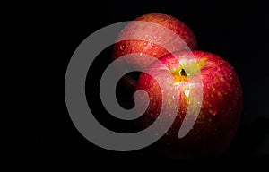 Water droplet on glossy surface of red apple on black background