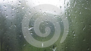 Close-up of water droplets on glass. Rain drops on window glass with blur background. Blurred tree and sky. Rainy days