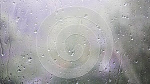 Close-up of water droplets on glass. Rain drops on window glass with blur background. Blurred tree and sky. Rainy days