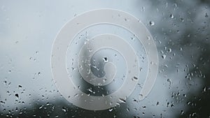 Close-up of water droplets on glass. Rain drops on window glass with blur background. Blurred tree and sky. Rainy days