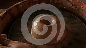 Close-up water drops falling on piece of raw clay on pottery wheel