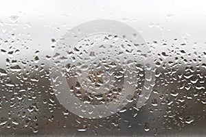 Close-up of water drops on the window glass. Rain drops on glass. Blurry backdrop, background, wallpaper, texture.