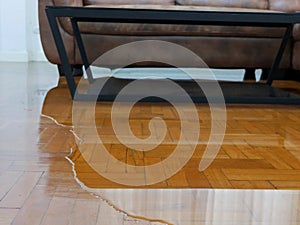 Close up of water flooding on living room parquet floor in a house - damage caused by water leakage