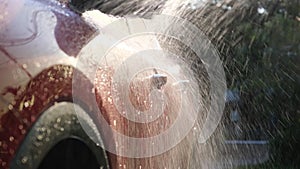 Close-up of water flowing on a car while a worker is using a high-pressure washer to wash the car. car wash service concept.