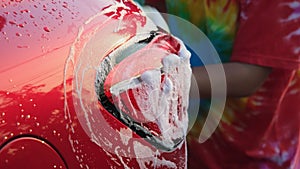 Close-up of water flowing on a car while a worker is using a high-pressure washer to wash the car. car wash service concept.