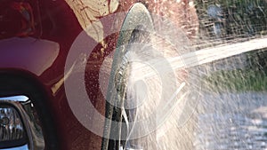 Close-up of water flowing on a car while a worker is using a high-pressure washer to wash the car. car wash service concept.