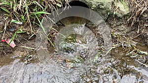 close up of water flowing down a drain into a ditch. waterways