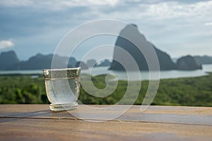 Close up of water glass on wood table in the morning sunrise of Samet Nang She is the best and famous view point on Phang nga bay