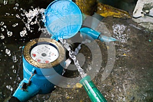 Close up water meter blue color. And a hose with flowing water.