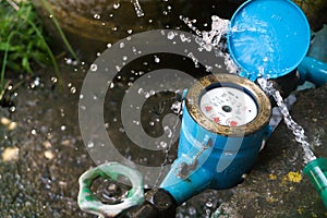 Close up water meter blue color. And a hose with flowing water.