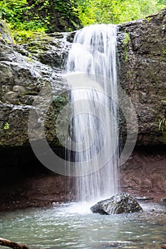 Close-up of a waterfall in the middle of a forest. Waterfall cascade on mountain rocks. Waterfall in the forest.