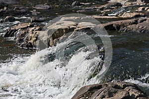 Close up of the waters of the Eno River cascading over boulders and rocks in Durham, North Carolina
