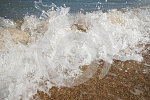 Close up wave on a sand beach, sea foam, splash of the sea