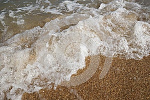 Close up wave on a sand beach, sea foam, splash of the sea