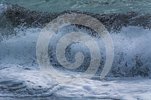 Close up waves hitting shore. Sea water surface with foam and ripples