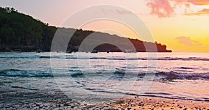 Close-up of waves spreading out over a beach at colorful sunset. Sea crystal bay. Reflection of sun rays on water