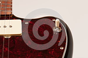 Close up of 3 way pickup switch on black electric guitar, studio shoot. Red tortoise shell pickguard, alder body, two single coil