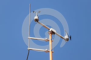 Close-up weather station wind speed direction measurement sensor gauge anemometer against clear blue sky background