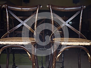 Close-up of weathered Brown wooden chairs placed and stacked in an empty room