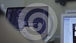 Close-up of web developer's hands programming Javascript, coding HTML on laptop. Stock. View from back