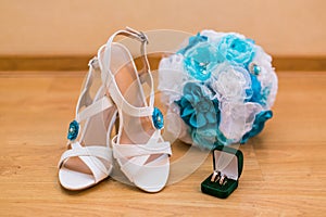Close up of wedding bouquet and bride's shoes and gold rings