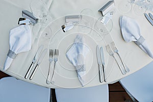 Close-up of a wedding dinner table. The cutlery is on the table - knives, forks, napkins with a ring for napkins