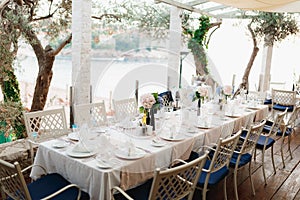 Close-up of a wedding dinner table at reception. A long table with metal chairs with blue pillows, in a stone gazebo