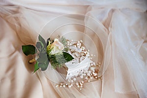 Close-up of wedding ornaments beautifully lies on a beige isolated background. The groom`s Bootery is a white rose, a