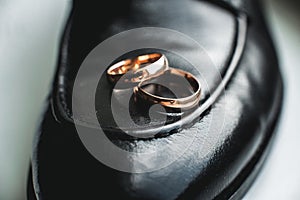 Close up of wedding rings on a black leather shoe