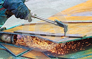 Close up of welder hand is cutting iron plate with acetylene gas welding torch machine at outdoor workshop