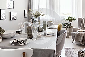 Well-laid table with plates and glasses in a grey dining room interior. Real photo photo