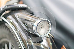 Close-up of a well-maintained vintage motorcycle, with emphasis on the headlight and engine components, captured from below and