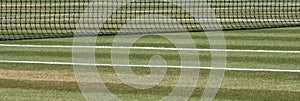 Close up of well manicured grass tennis court with net in the background at Wimbledon, London UK