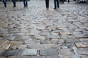 A close-up on a wet durable stone pebbled walkway, cobblestone pedestrian shared street of an old city