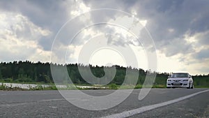 Close-up wheel sport. The scene behind as the sun going down with wind turbines in the back. white sport car on the road