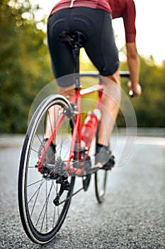 close-up wheels of bicycle, rear view on man with athletic body shape iriding bicycle