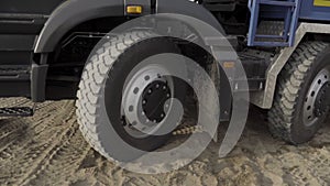 Close up of wheels of a slowly moving truck on sandy surface. Scene. construction site background.