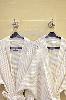 Close up of white bathrobes hanging on classic stone wall