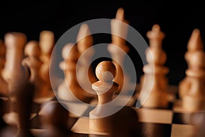 Close up of white and black chess pieces on board. Selective focus on first move of white pawn on chessboard. Concept of