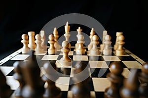 Close up of white and black chess pieces on board. Selective focus on first move of white pawn on chessboard. Concept of