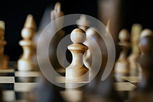 Close up of white and black chess pieces on board. Selective focus on first move of white pawn on chessboard. Concept of