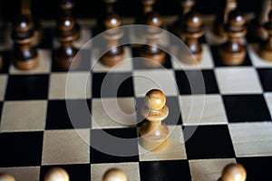 Close up of white and black chess pieces on board. Selective focus on first move of white pawn on chessboard. Concept of