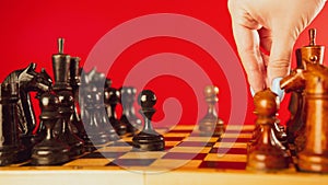 Close up of white and black wooden chess pieces on board. Woman& x27;s hand makes move of white pawn on chessboard. Concept