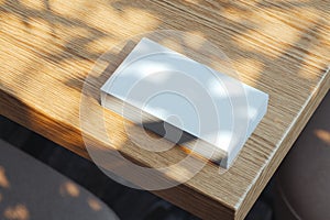 Close up of white blank illuminated by daylight business cards set on wooden table, 3d rendering.