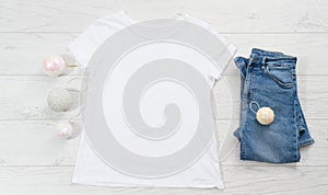 Close up white blank template t shirt with copy space and Christmas Holiday concept. Top view mockup t-shirt and jeans on white